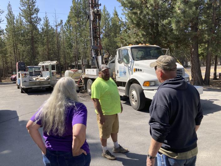 Linda Jincks and her husband Rodger talk with driller Shane Harris as his crew drills a new well for the Jincks at their home in La Pine, Ore., on Aug. 26, 2021. Sheriff's deputies busted an illegal marijuana grow a block away recently and another, bigger grow had been nearby, using water from the same aquifer that the neighborhood uses. (AP Photo/Andrew Selsky)