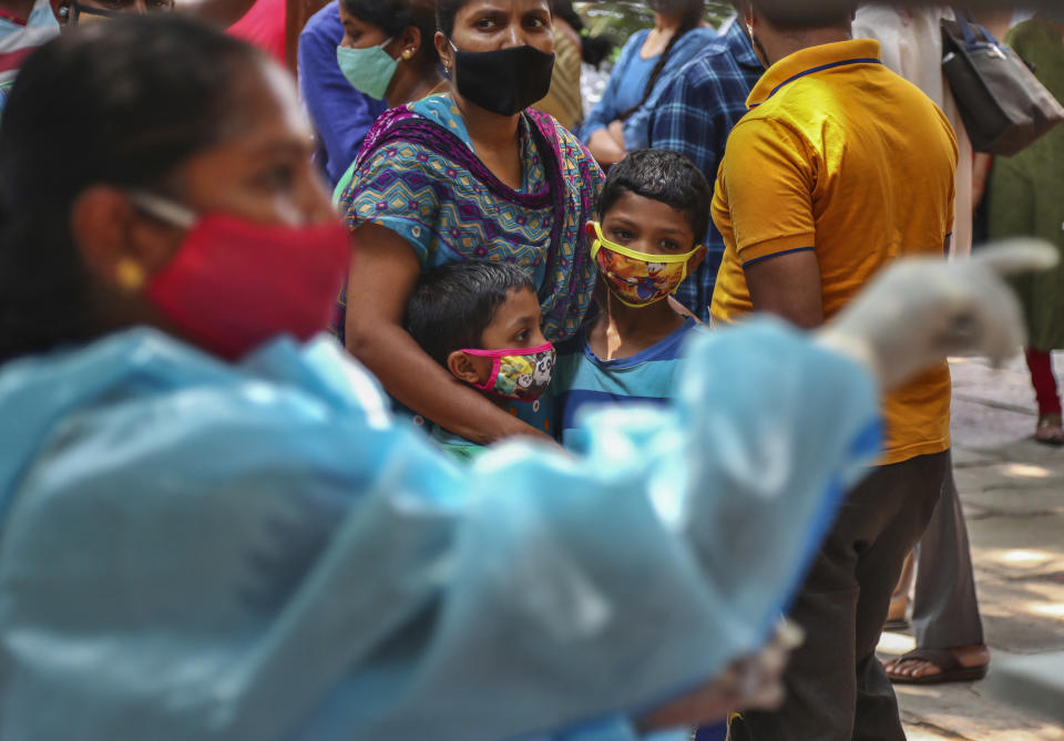 A woman holds on to two children as they wait their turn to get tested for COVID-19 in Hyderabad, India, Sunday, April 25, 2021. After having largely tamed the virus last year, India is in the throes of the world’s worst coronavirus surge and many of the country’s hospitals are struggling to cope with shortages of beds, medicines and oxygen. (AP Photo/Mahesh Kumar A.)