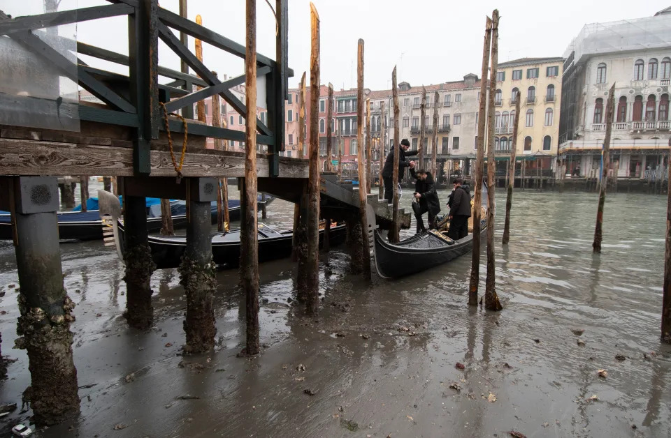 Passengers get off a gondola docked along a canal during a low tide in Venice, Italy, Tuesday, Feb. 21, 2023. Some of&nbsp;Venice's secondary canals have practically dried up lately due a prolonged spell of low tides linked to a lingering high-pressure weather system.