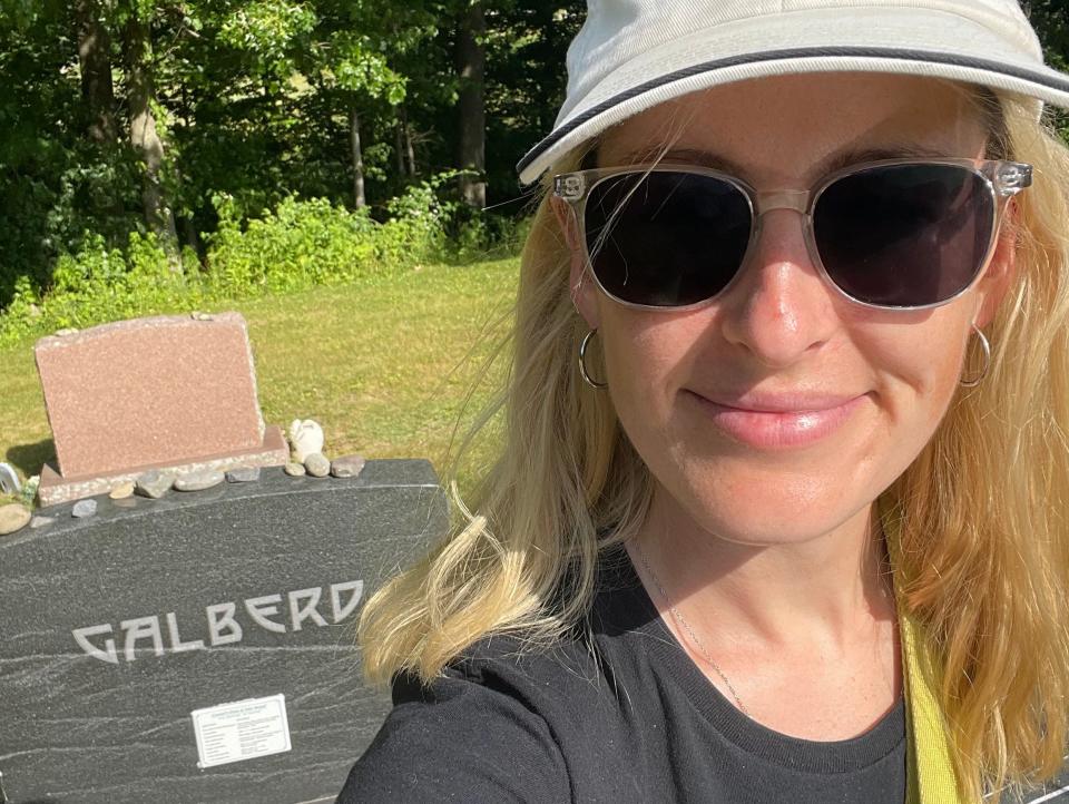 Rosie Grant poses in a graveyard with one of her gravestone recipes for TikTok.