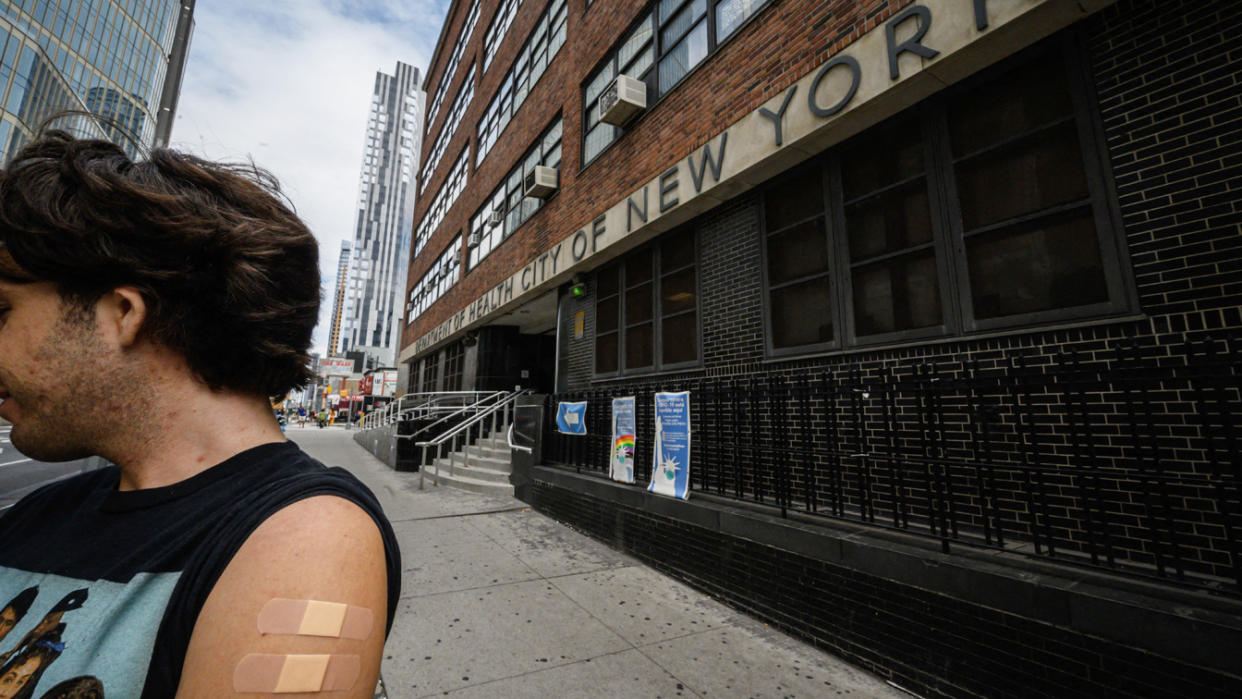 A man outside a health clinic displays his arm where he received a polio vaccination.