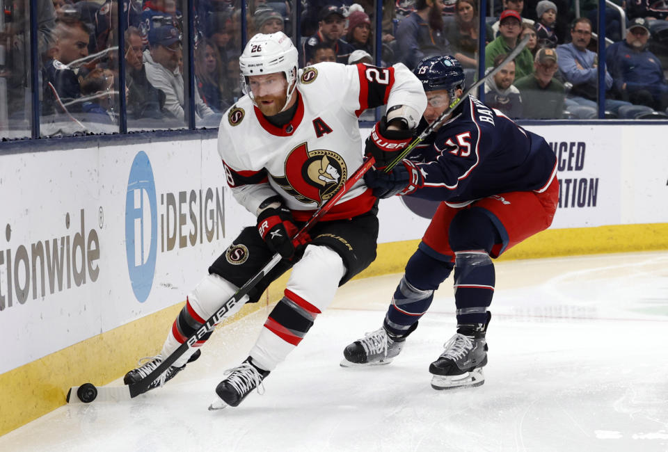 Ottawa Senators forward Claude Giroux, left, controls the puck in front of Columbus Blue Jackets defenseman Gavin Bayreuther during the first period of an NHL hockey game in Columbus, Ohio, Sunday, April 2, 2023. (AP Photo/Paul Vernon)