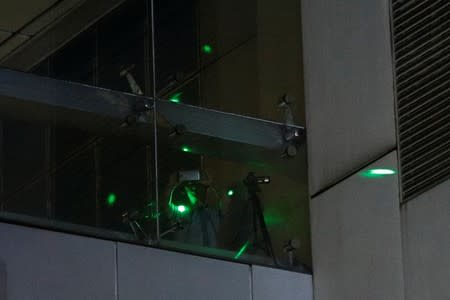 Anti-extradition demonstrators use a laser pointer to distract a man inside of Chinese Liaison Office after a march to call for democratic reforms, in Hong Kong