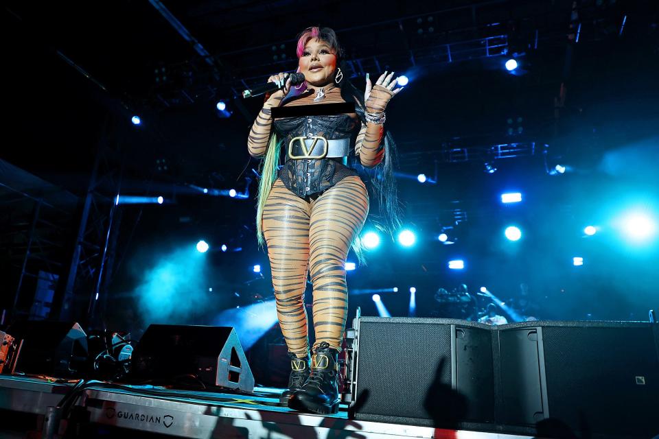 Lil' Kim in a black leather bodysuit and striped leggings on stage