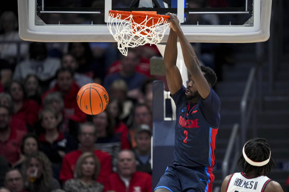 Duquesne forward David Dixon (2) dunks the ball against Dayton forward DaRon Holmes II during the first half of an NCAA college basketball game, Tuesday, Feb. 13, 2024, in Dayton, Ohio. (AP Photo/Aaron Doster)