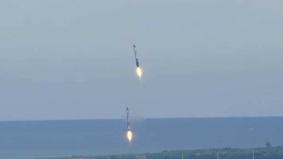 Two rockets come down for a landing with the ocean in the background