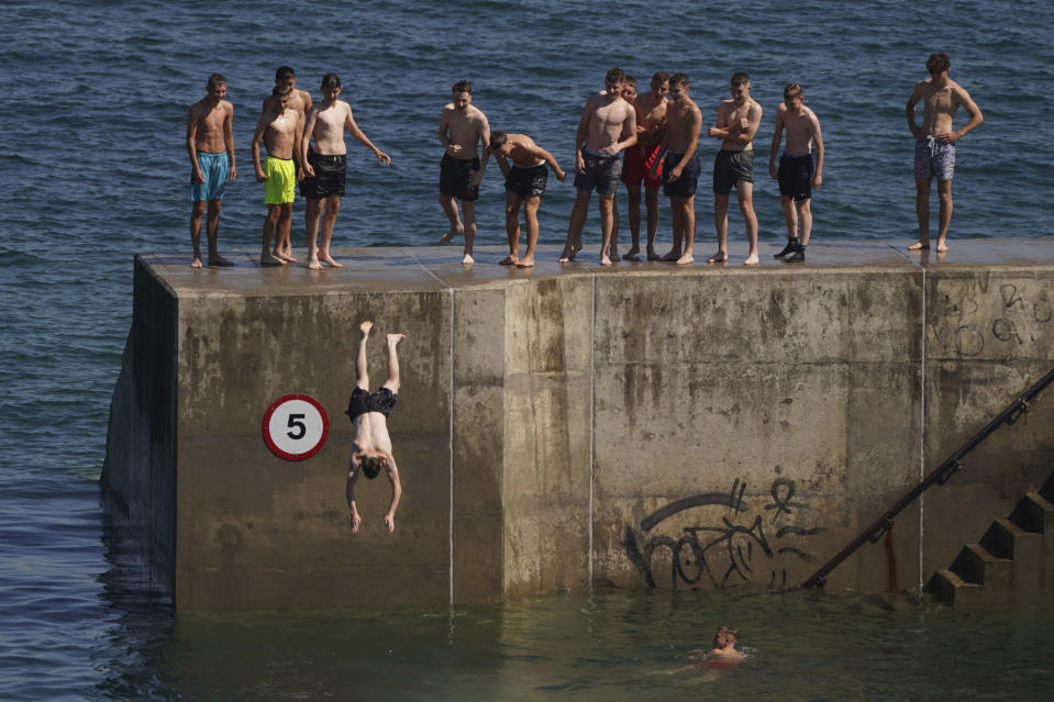 A group of young men cool off in the hot weather by diving into the water at Cullercoats Bay in North Tyneside, England, Wednesday Aug. 10, 2022. The Met Office has issued an amber warning for extreme heat covering four days from Thursday to Sunday for parts of England and Wales as a new heatwave looms. (Owen Humphreys/PA via AP)