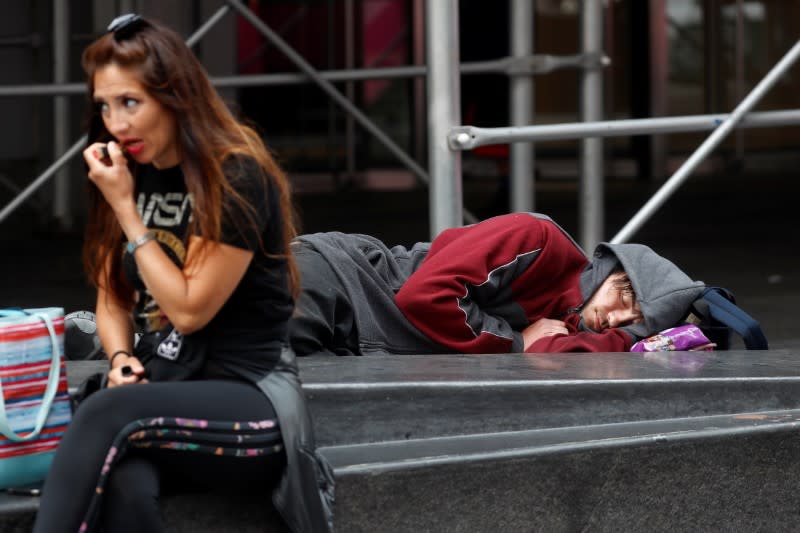 A man lays on a bench at Times Square in New York City