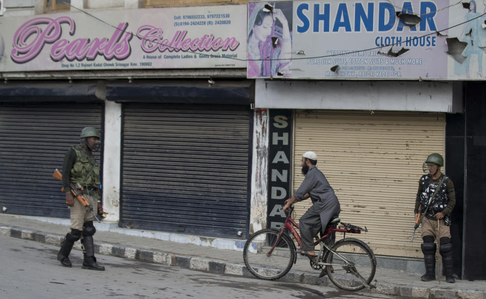 A Kashmiri cyclist rides past Indian Paramilitary soldiers as they stand guard during curfew in Srinagar, Indian controlled Kashmir, Wednesday, Aug. 7, 2019. Authorities in Hindu-majority India clamped a complete shutdown on Kashmir as they scrapped the Muslim-majority state's special status, including exclusive hereditary rights and a separate constitution, and divided it into two territories. (AP Photo/Dar Yasin)