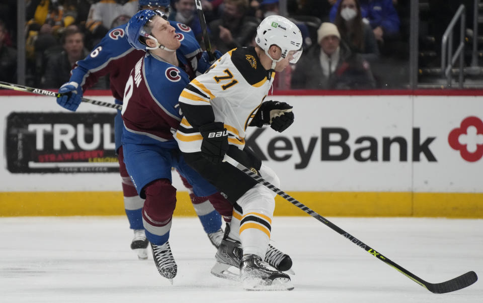 Colorado Avalanche center Nathan MacKinnon, left, collides with Boston Bruins left wing Taylor Hall in the first period of an NHL hockey game Wednesday, Jan. 26, 2022, in Denver. (AP Photo/David Zalubowski)