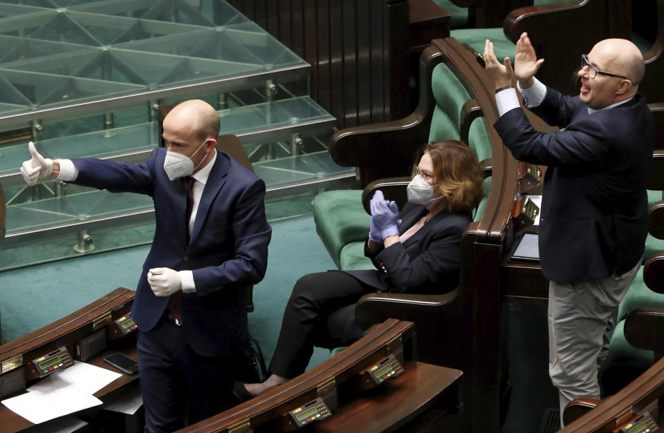 Borys Budka, left, head of the opposition Civic Platform and the party's presidential candidate Malgorzata Kidawa-Blonska,center, react during a parliamentary session, in Warsaw, Poland, on Monday, April 6, 2020. Uncertainty over whether Poland will hold a postal presidential election during the coronavirus pandemic deepened Monday after a deputy prime minister resigned, leaving Kaczynski's ruling party without enough votes to approve an exclusively mail-in ballot. The opposition lawmakers oppose the postal vote in May and are calling for a state of emergency so that the vote can be delayed until after the pandemic. (AP Photo/Czarek Sokolowski)