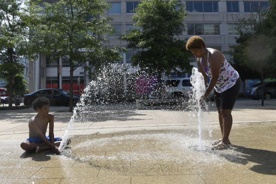 Karen Frazier of Capitol Heights, Md., right, and her son Amari Rogers, 11, left, play in a fountain in Washington, Saturday, July 20, 2019. The National Weather Service said "a dangerous heat wave" was expected to break record highs in some places, particularly for nighttime. (AP Photo/Susan Walsh)