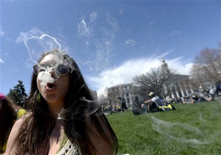 A woman blows smoke rings with marijuana smoke during the 4/20 Rally at the Civic Center in Denver, Colorado, April 20, 2014. REUTERS/Mark Leffingwell