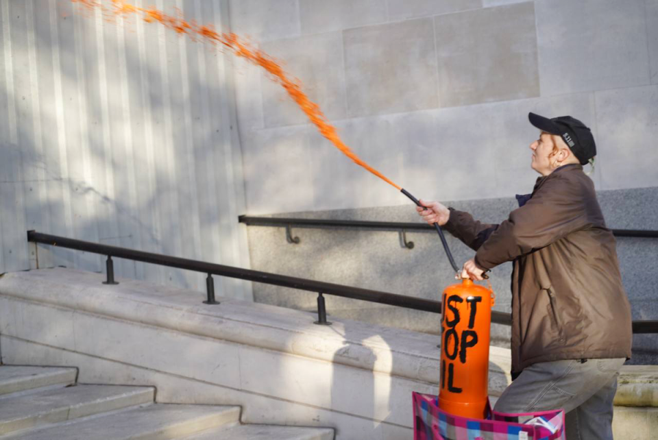 A woman sprays paint onto the MI5 building at Vauxhall Cross (Just Stop Oil)