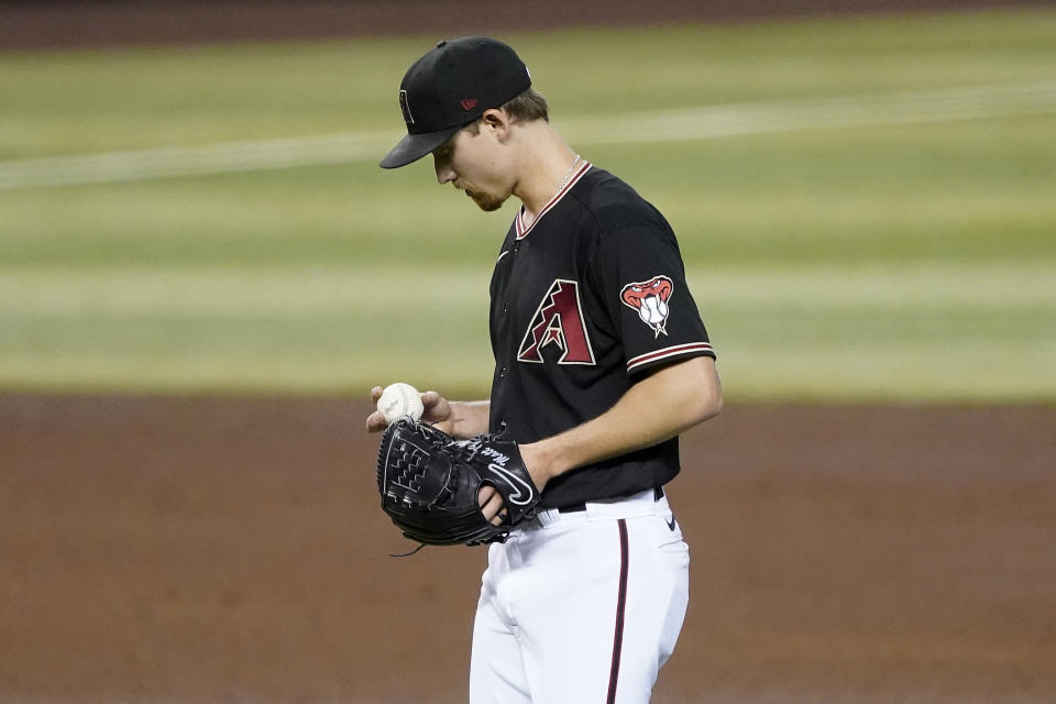 Arizona Diamondbacks starting pitcher Luke Weaver looks at the baseball after giving up a home run to the Colorado Rockies during the fourth inning of a baseball game, Saturday, Sept. 26, 2020, in Phoenix. (AP Photo/Matt York)