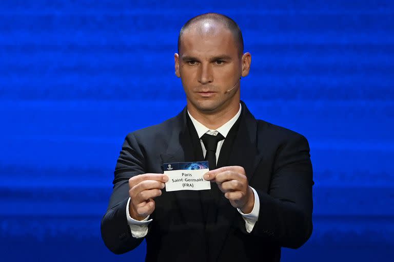 El defensor serbio Branislav Ivanovic muestra el nombre de Paris-Saint Germain durante el sorteo de grupos de la Champions League; detrás, una carrera de intereses entre dos países no europeos.