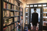 Tom, shop manager of Broadway Bookshop in Broadway Market, Hackney, in east London, holds two bags of books to be collected by customers as the business had to be converted to cope with the lockdown measures due to the coronavirus outbreak, on June 18, 2020. Before the pandemic, shoppers would pack the tidy shop on weekends, with more often waiting outside, drawn by the store’s personalized service. (AP Photo/Alberto Pezzali)