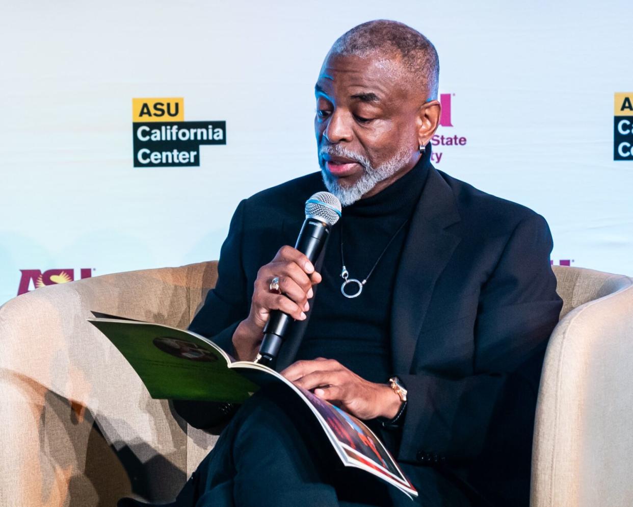 A man reads into a microphone from a book