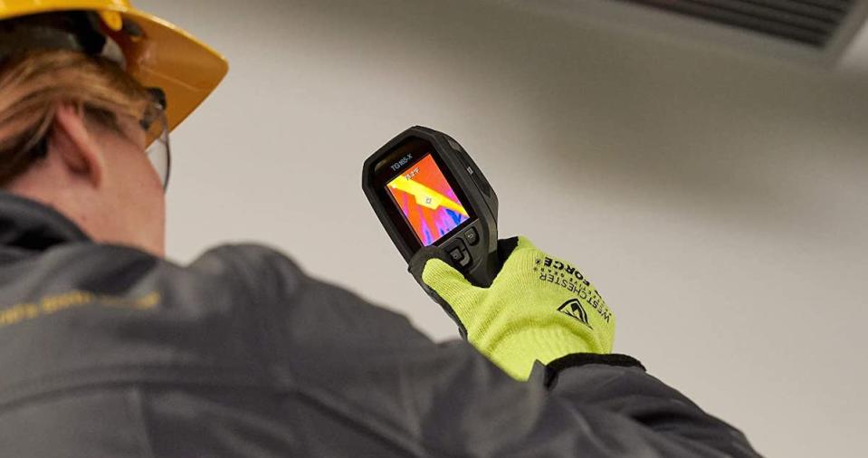 Fireman wearing gloves and holding a thermal camera in his hand.