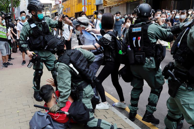 FILE PHOTO: Anti-government demonstrators scuffle with riot police during a lunch time protest as a second reading of a controversial national anthem law takes place in Hong Kong