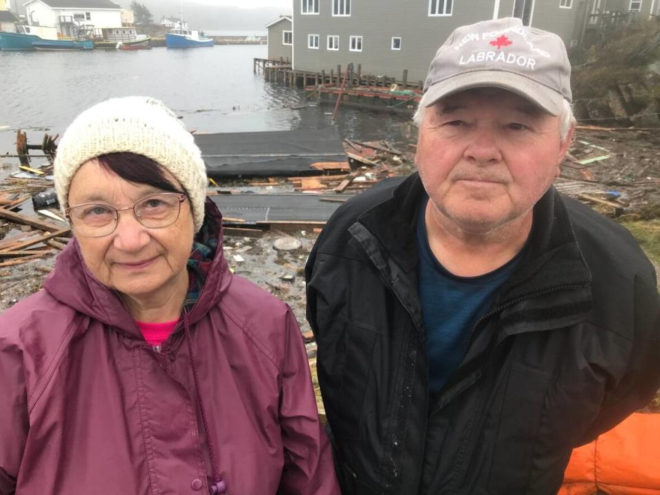 Arthena and Hedley King stand next to what is left of their fishing shed and wharf in Rose Blanche. Hedley, right, has been a fish harvester for 35 years. (Terry Roberts/CBC - image credit)