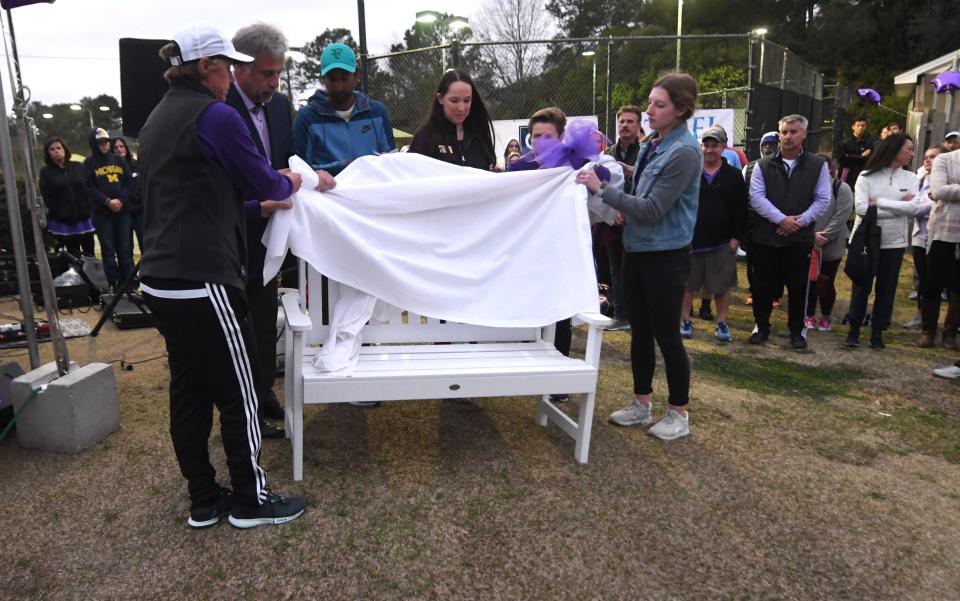Rachel Knowles, right, helps unveil a bench in honor of her mother MaryAnn Breault during a ceremony at Holly Tree Racquet Club in Wilmington, N.C., Friday, March 4, 2022. Breault was killed in a murder-suicide domestic violence dispute in front of the club on December 7. El was a friend of Breault and a victim of domestic violence herself.    [MATT BORN/STARNEWS]