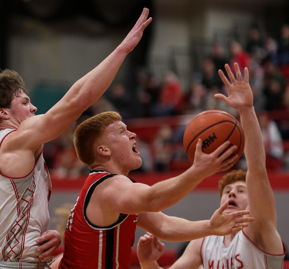 Monroe’s Logan Frank goes to the basket against Bedford defenders Tommy Huss (left) and Simon Eighmey Friday night. Bedford won 62-43.