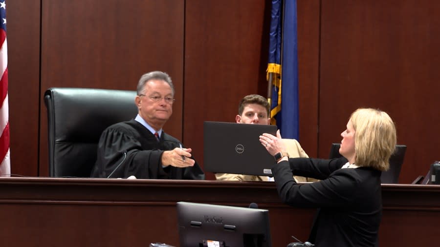 Senior Assistant Deputy Attorney General Heather Weiss hands up her laptop to Circuit Court Judge Michael Nettles so he could watch the body camera recording of the May 2020 jailhouse assault of Jarrel Johnson during this Dec. 21, 2021, arraignment hearing of Charles Lemon and Andrew Cook. (WJZY Photo/Jody Barr)