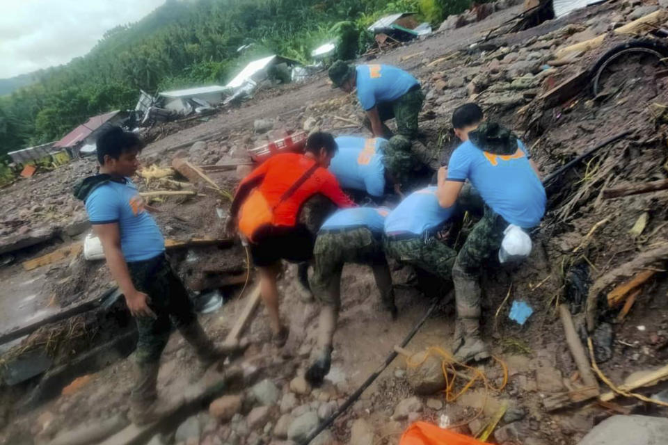 In this handout photo provided by the Philippine Coast Guard, rescuers retrieve bodies during the search and rescue operations due to landslides caused by Tropical Storm Nalgae in Barangay Kushong, Datu Odin Sinsuat, Maguindanao province, southern Philippines on Friday Oct. 28, 2022. Several people died while others were missing in flash floods and landslides set off by torrential rains from Tropical Storm Nalgae that swamped a southern Philippine province overnight and trapped some residents on their roofs, officials said Friday.(Philippine Coast Guard via AP)