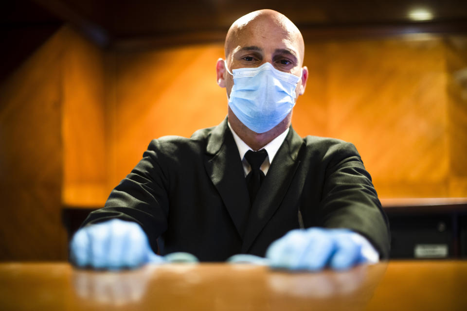 Concierge Joe DeLuca, poses for a photograph at the front desk of an apartment building in New York, April 6, 2020. While tens of thousands of New Yorkers work at home during the COVID-19 pandemic, people like DeLuca keep the city running amid the lockdown. (AP Photo/Matt Rourke)