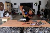 Visual artist Adeyemi Emmanuel attaches cut pieces of wooden frames to a bag in his art studio in Lagos, Nigeria