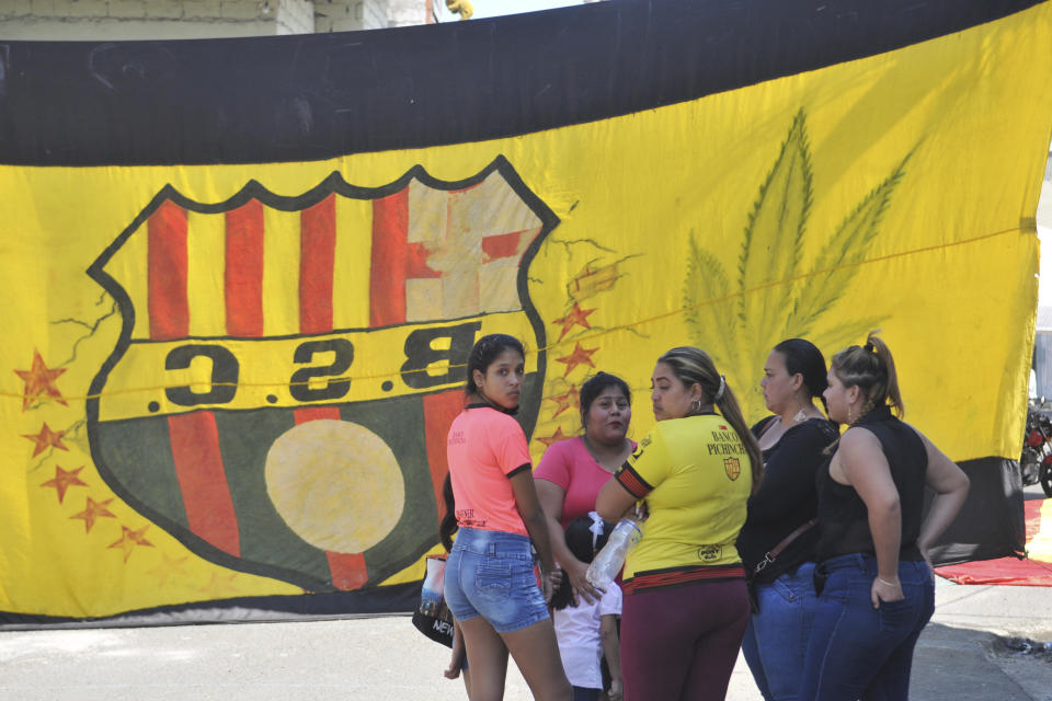 Un grupo de mujeres conversa frente a la casa de un hincha del Barcelona de Ecuador, fallecido junto con otros 11 en un accidente de autobús, el lunes 13 de agosto de 2018 (AP Foto/José Sánchez)