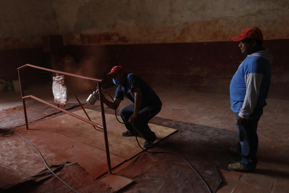 A worker sprays primer onto a railing inside the former San Juan Bautista Convent, where restoration work is underway following damage in a 2017 earthquake, in Tlayacapan, Morelos state, Mexico, Tuesday, Oct. 13, 2020. “Imagine, these structures sometimes took as long as 100 years to be built ... and in three years, we have managed to consolidate the structure,” said architect Fernando Duarte Soriano, who is restoring churches for the Institute, known as the INAH, in Morelos state. (AP Photo/Rebecca Blackwell)