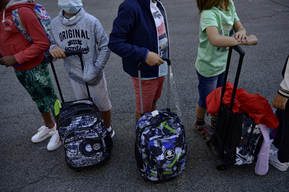 A group of young students wearing face mask protection to prevent the spread of the coronavirus wait in the courtyard of a state school, in Pamplona, northern Spain, Friday, Sept. 4, 2020. After six months with all Spanish schools closed by crisis of COVID-19, today is opening a new school year with new rules to prevent the pandemic coronavirus. (AP Photo/Alvaro Barrientos)