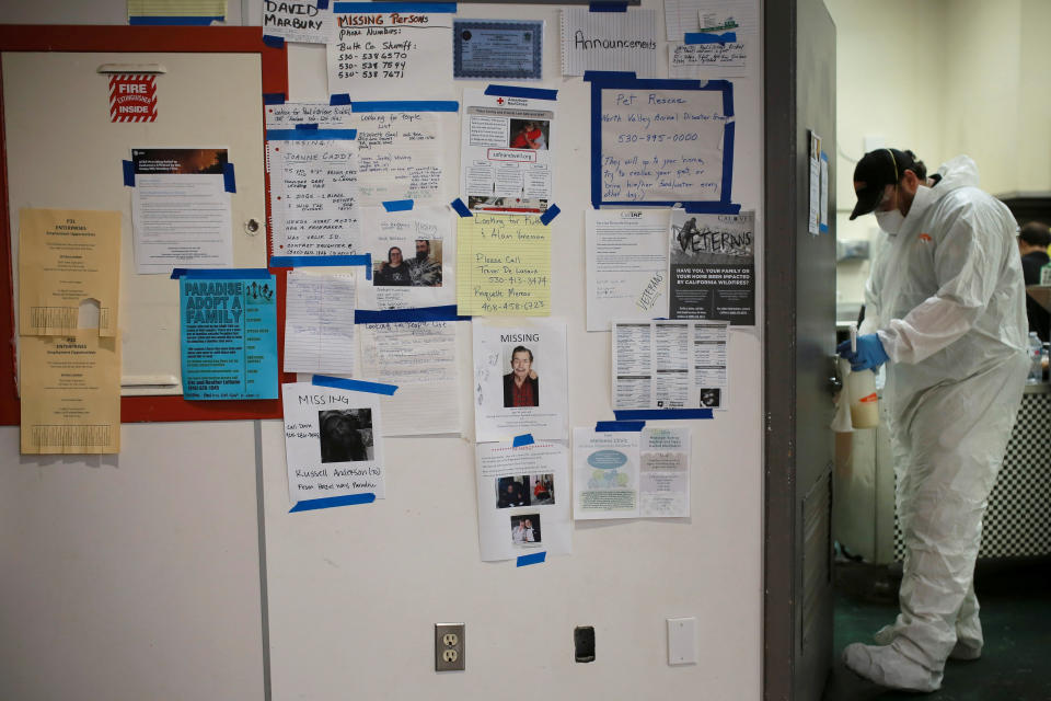 Missing persons fliers are seen on a wall as a man disinfects a door handle at a Red Cross shelter at Bidwell Junior High School in Chico, California, U.S. November 20, 2018. REUTERS/Elijah Nouvelage