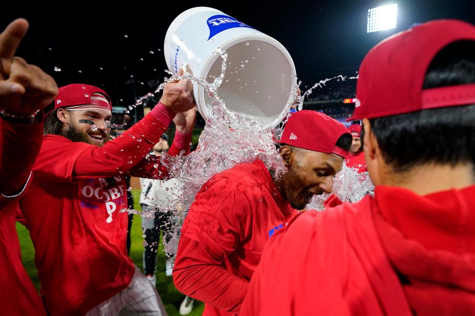 Philadelphia Phillies' Johan Rojas, right, is dunked by Philadelphia Phillies' Brandon Marsh to celebrate after winning a baseball game against the Pittsburgh Pirates to clinch a wild-card playoff spot, Tuesday, Sept. 26, 2023, in Philadelphia.