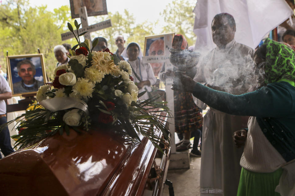 A woman burns incense over the remains of Jesuit priests Javier Campos Morales and Joaquin Cesar Mora Salazar in Cerocahui, Chihuahua state, Mexico, Sunday, June 26, 2022. The two elderly priests and a tour guide murdered in Mexico's Sierra Tarahumara this week are the latest in a long line of activists, reporters, travelers and local residents who have been threatened or killed by criminal gangs that dominate the region. (AP Photo/Christian Chavez)