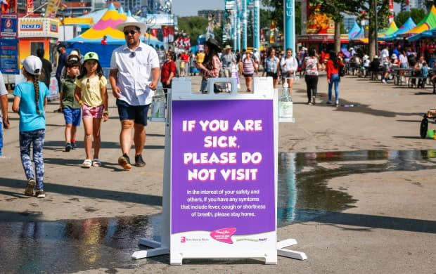 A COVID precaution sign at the Calgary Stampede on July 9, 2021. The Stampede is offering free admission for the final day of the festival, on Sunday, July 18. (Jeff McIntosh/Canadian Press - image credit)