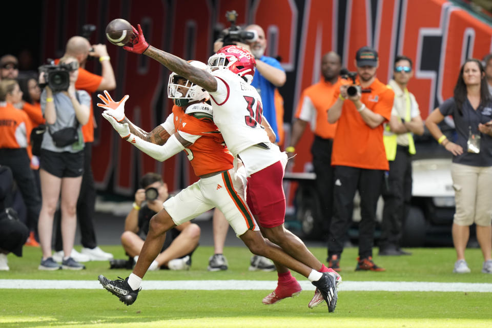 Louisville defensive back Derrick Edwards (30) swats a pass away from Miami wide receiver Jacolby George during the second half of an NCAA college football game, Saturday, Nov. 18, 2023, in Miami Gardens, Fla. (AP Photo/Wilfredo Lee)