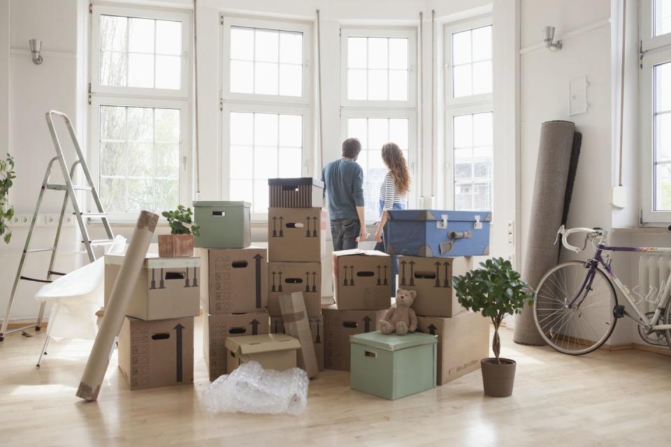 couple with cardboard boxes in new apartment looking out of window