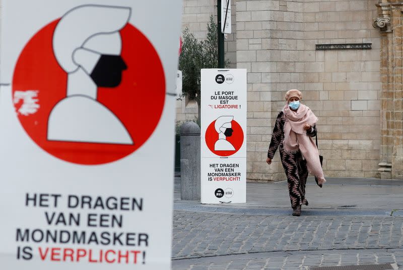 A woman walks past a sign announcing the mandatory use of masks amid the coronavirus disease outbreak in Brussels