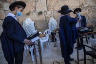 Ultra-Orthodox Jewish men wear protective mace masks during morning prayer at the Western Wall, the holiest site where Jews can pray, in Jerusalem's old city, Thursday, July 16, 2020. The Western Wall plaza is divided to sections which allowed maximum twenty people following the government's measures to help stop the spread of the coronavirus. (AP Photo/Oded Balilty)