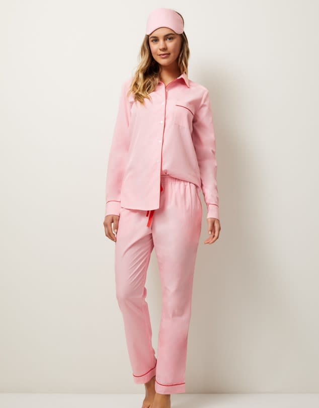 A model standing in pink pyjamas with matching eye mask