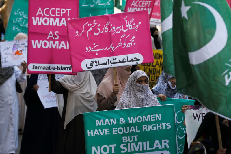Women supporters of the religious and political party Jamaat-e-Islami (JI) hold signs as they take part in an Aurat March, or Women's March, in Karachi