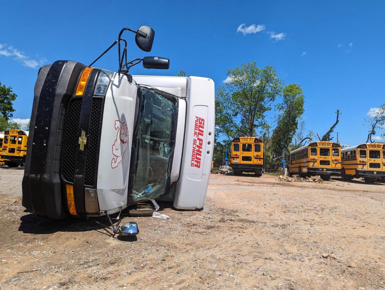 A Sulphur Public Schools van lays overturned among school buses after a tornado ripped through the small town Saturday evening.