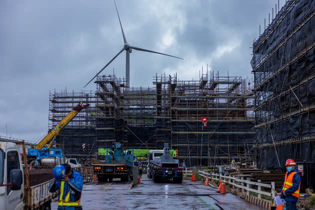 A wind turbine rises behind a construction site for a natural gas power plant in Taoyuan, Taiwan.