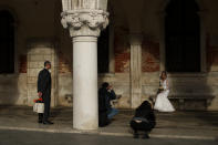 A woman wearing a bridal dress poses for photographs near St. Mark's square in Venice, Italy, Tuesday, March 3, 2020. Venice in the time of coronavirus is a shell of itself, with empty piazzas, shuttered basilicas and gondoliers idling their days away. Venice, a UNESCO world heritage site, had already been brought to its knees last year, when near-record high tides flooded a lagoon city used to frequent spells of "aqua alta." (AP Photo/Francisco Seco)