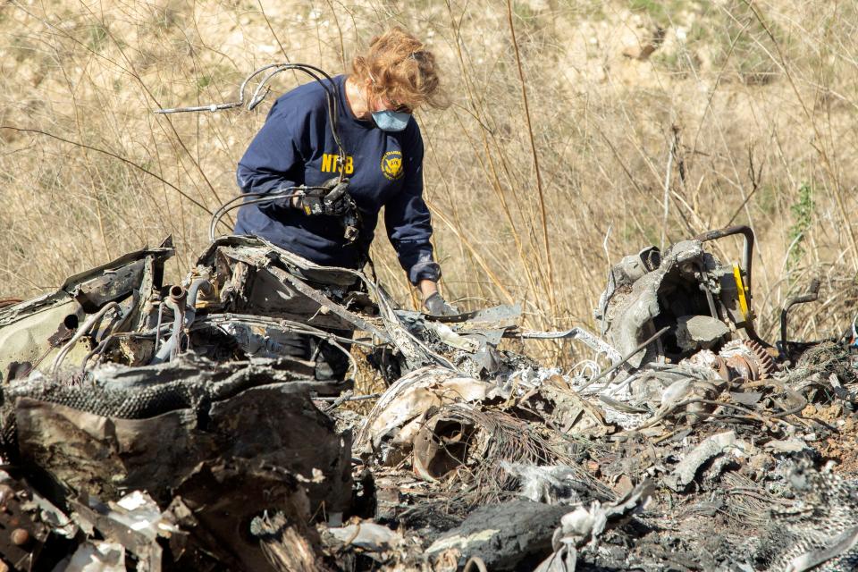 In a photo released by the National Transportation Safety Board, an NTSB investigator examines wreckage from the helicopter crash that killed Kobe Bryant, his 13-year-old daughter, Gianna, and seven others.