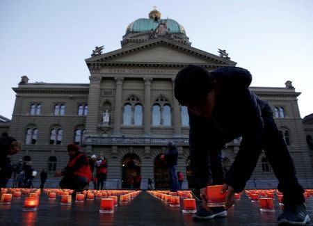 People place candles during the "One Million Candles" event by Swiss humanitarian organization Caritas as a sign of solidarity and cohesion with the infirm and the poor, at the parliament square in Bern, Switzerland December 10, 2016. REUTERS/Ruben Sprich/Files