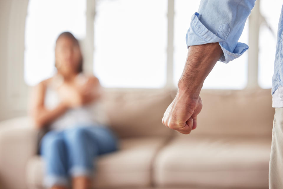 Closeup shot of a frustrated, abusive mans fist before harming his fearful wife on the sofa and showing signs of being in a toxic relationship